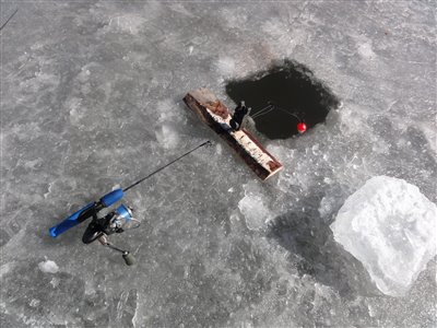 Der fiskes gedder på isen med levende agnfisk, flåd og bidmelder.